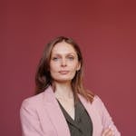 Elegant businesswoman with arms crossed in studio portrait, showcasing leadership and confidence.