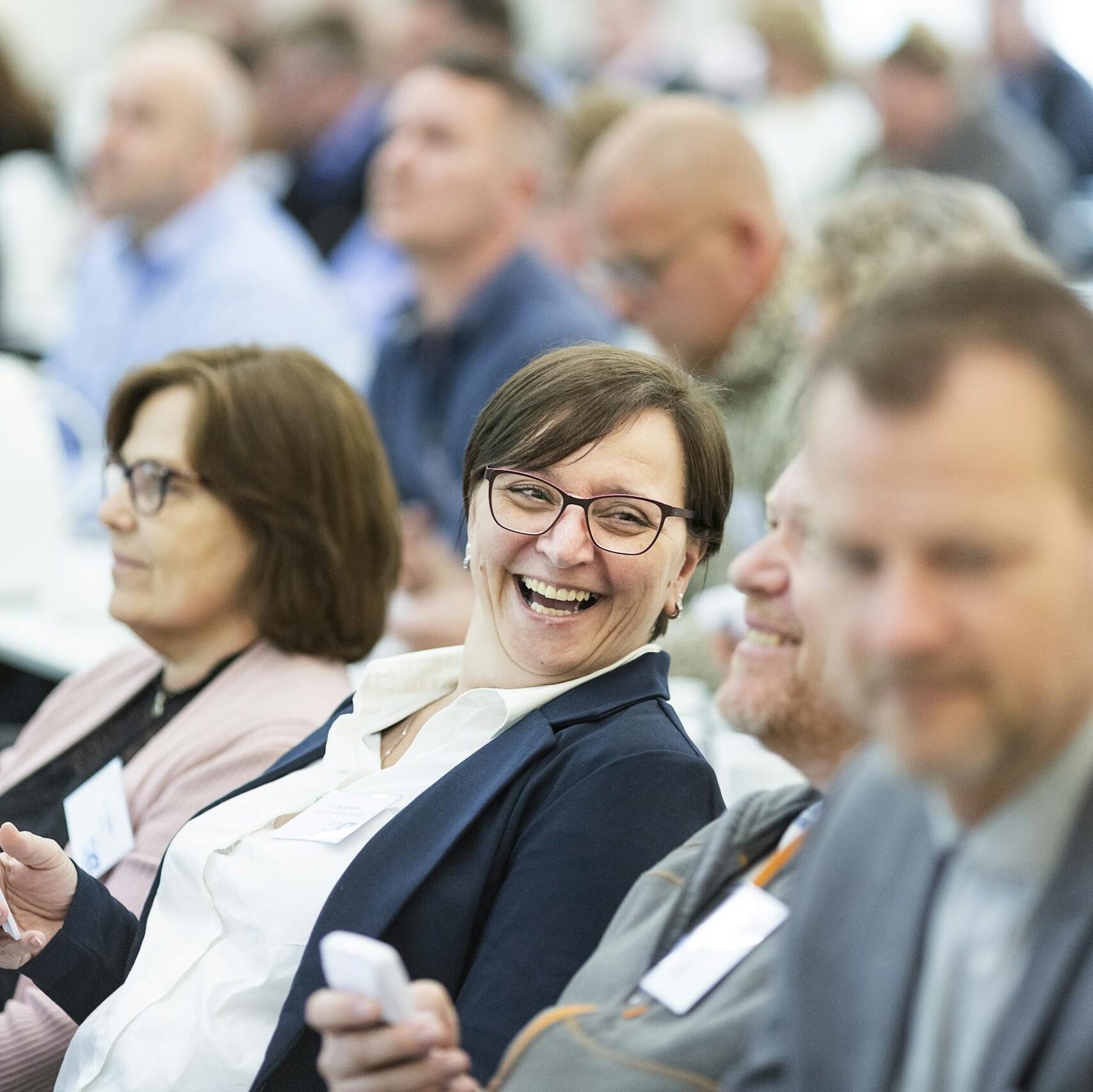 Group of diverse adults smiling and engaging during an indoor business meeting, showcasing teamwork.