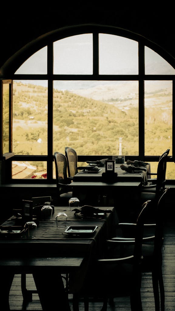 Elegant indoor dining with scenic mountain view through arched windows.
