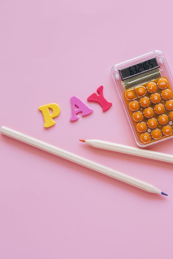 Vibrant school supplies and calculator on a pink surface symbolizing education and finance concepts.