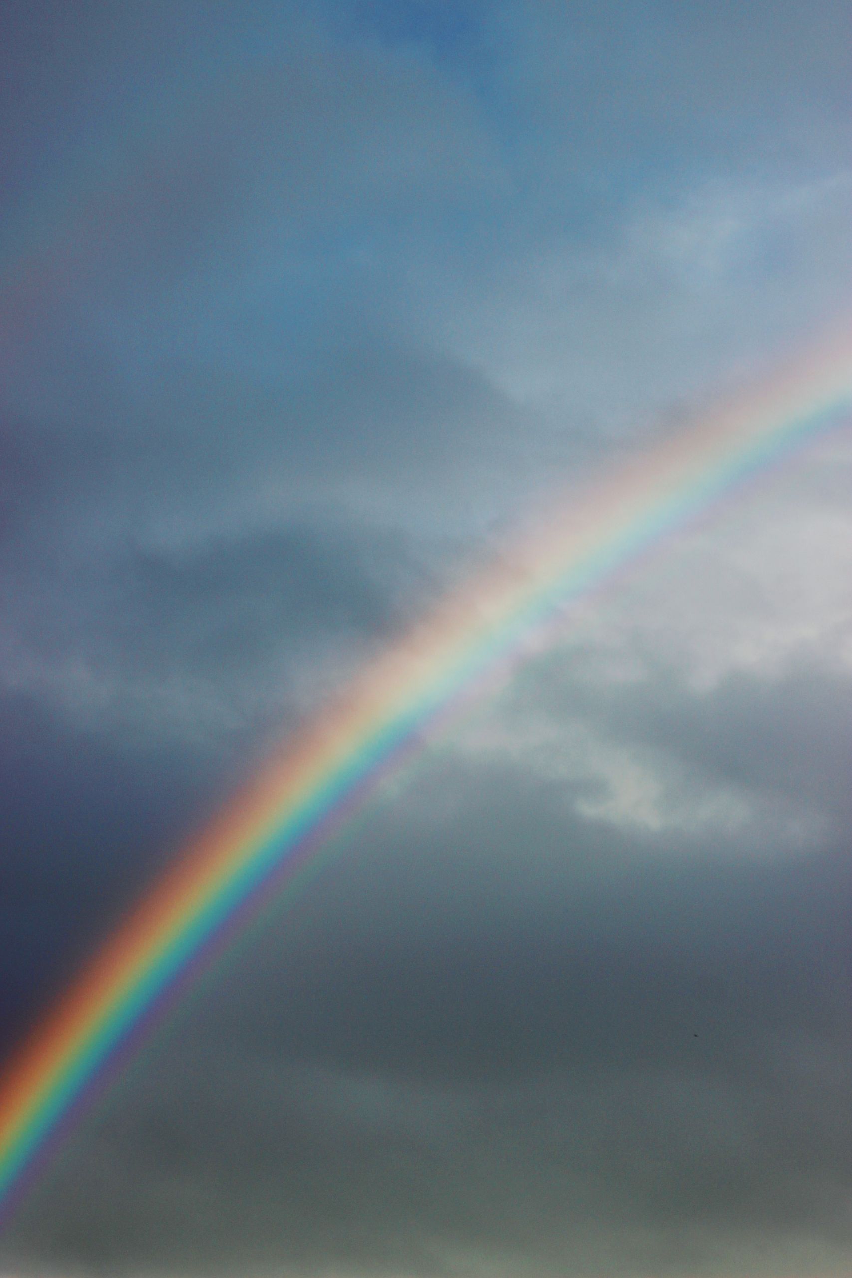 A striking rainbow arcs across a cloudy sky, showcasing vibrant colors against the moody backdrop.